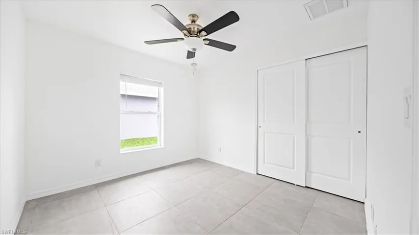 Unfurnished bedroom featuring light tile patterned floors, a ceiling fan, and a closet