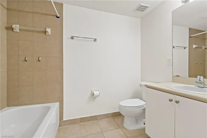 Full bathroom with toilet, tile patterned flooring, vanity, a textured ceiling, and tiled shower / bath