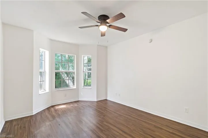 Empty room with ceiling fan and dark hardwood / wood-style flooring