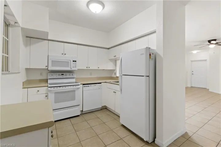 Kitchen featuring ceiling fan, white cabinetry, white appliances, and light tile patterned floors