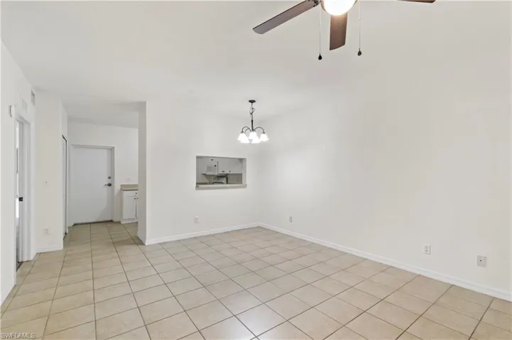 Unfurnished living room with ceiling fan with notable chandelier and light tile patterned floors