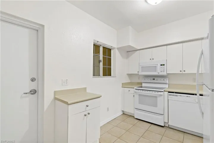 Kitchen featuring white cabinets, white appliances, and light tile patterned floors