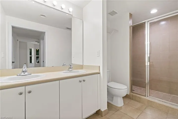 Bathroom with tile patterned floors, an enclosed shower, vanity, and toilet