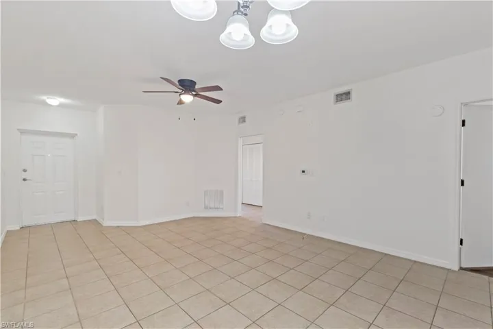 Unfurnished room featuring light tile patterned floors and ceiling fan with notable chandelier
