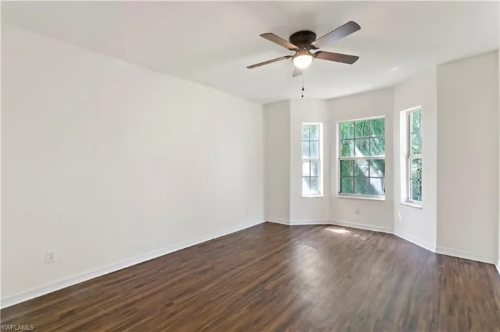 Empty room with ceiling fan and dark wood-type flooring