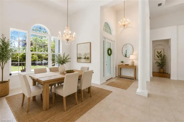 Vaulted ceilings highlight a grand entry with a crystal chandelier and an arched transom window above the front door