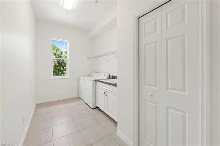 Utility room with tile flooring, white cabinetry, a built-in sink, upper shelving, and a window