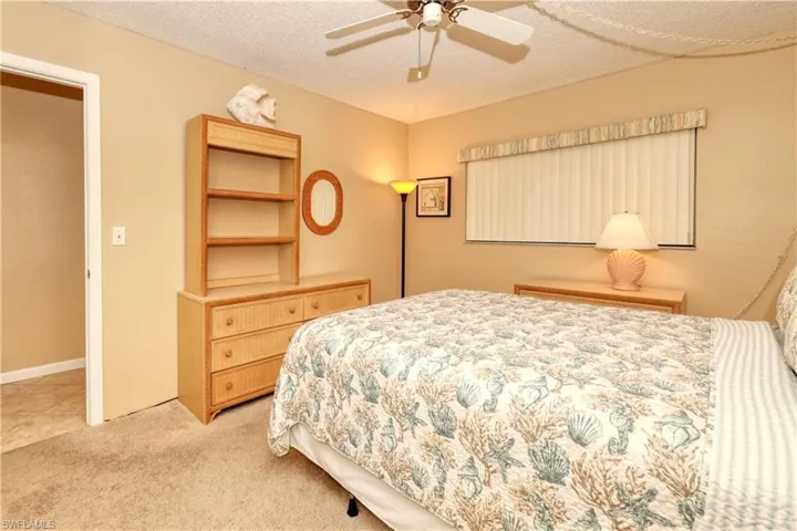 Bedroom with light carpet, a ceiling fan, and a textured ceiling