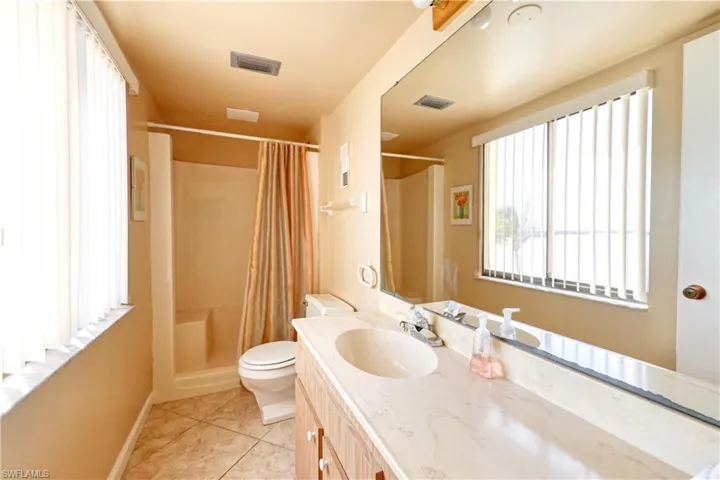 Full bath featuring a shower with curtain, visible vents, toilet, vanity, and tile patterned flooring