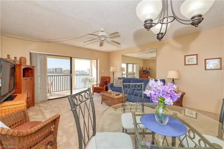 Carpeted dining space with ceiling fan with notable chandelier and a textured ceiling