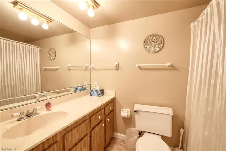 Bathroom featuring tile patterned flooring, baseboards, vanity, and toilet