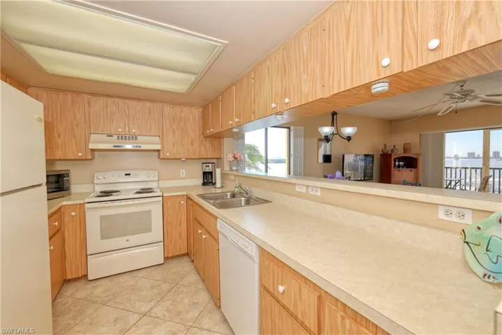 Kitchen featuring ceiling fan, sink, decorative light fixtures, white appliances, and light tile patterned flooring