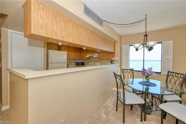 Carpeted dining room featuring a textured ceiling, a water view, and an inviting chandelier