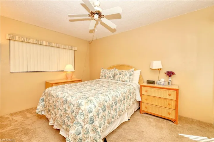 Carpeted bedroom with a ceiling fan and a textured ceiling