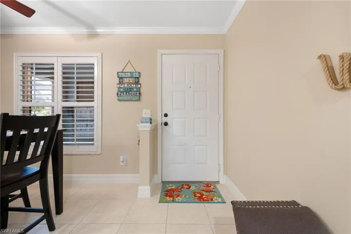 Tiled foyer entrance with ceiling fan and crown molding