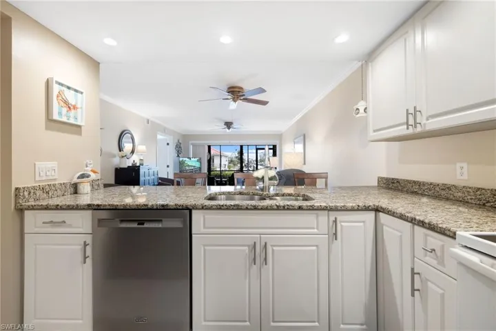Kitchen with dishwasher, white cabinets, sink, kitchen peninsula, and ornamental molding