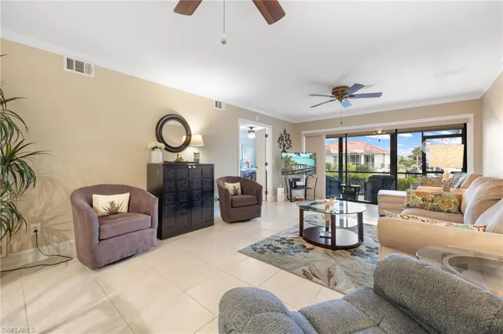 Tiled living room with crown molding and ceiling fan