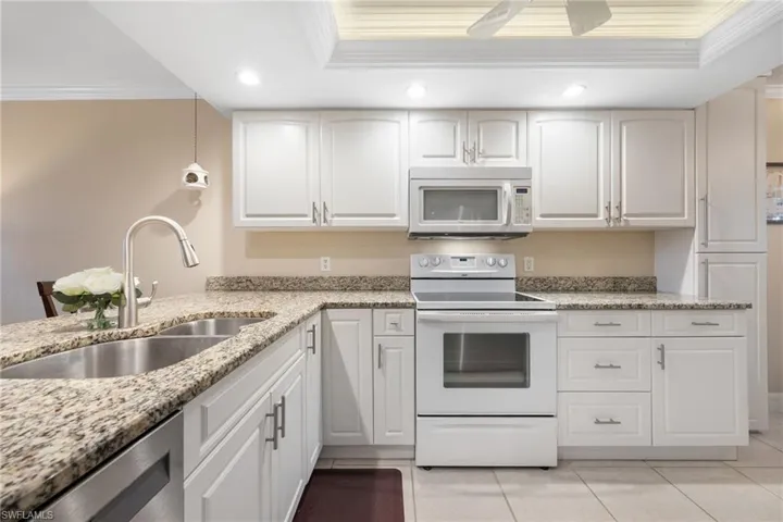 Kitchen with sink, white cabinetry, white appliances, and ornamental molding