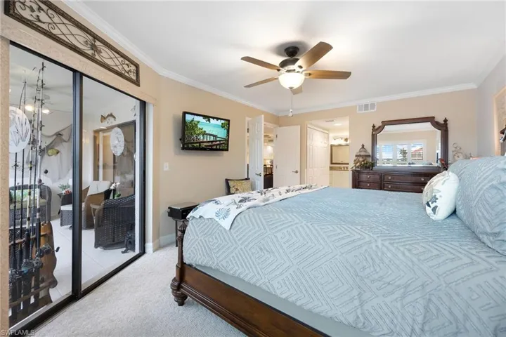 Carpeted bedroom featuring ceiling fan, a closet, and ornamental molding