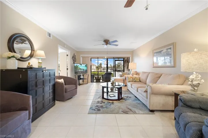 Living room with ceiling fan, light tile patterned floors, and ornamental molding