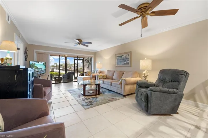 Living room featuring ceiling fan, light tile patterned floors, and ornamental molding