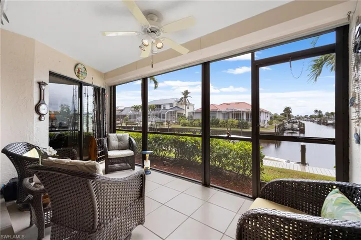Sunroom with ceiling fan and a water view