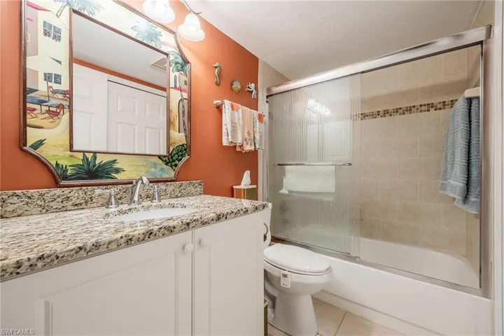 Full bathroom featuring enclosed tub / shower combo, tile patterned floors, vanity, and toilet
