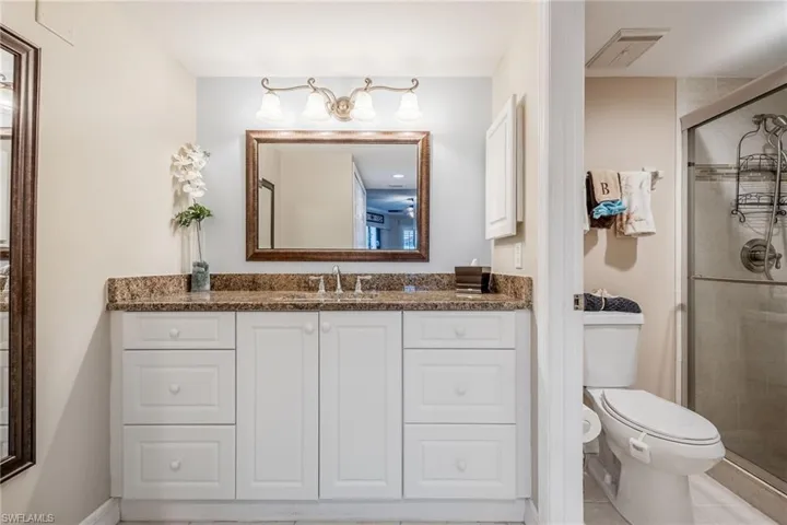 Bathroom featuring toilet, an enclosed shower, tile patterned floors, and vanity