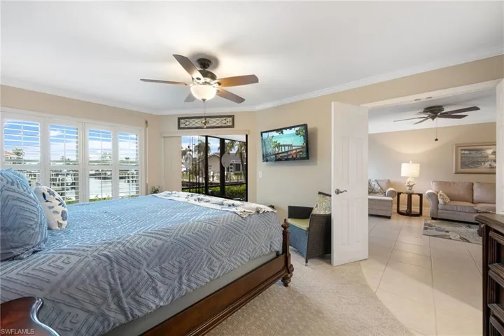 Tiled bedroom with crown molding, ceiling fan, and access to outside
