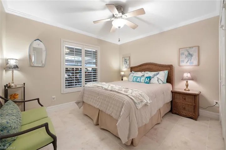 Tiled bedroom with ceiling fan and ornamental molding