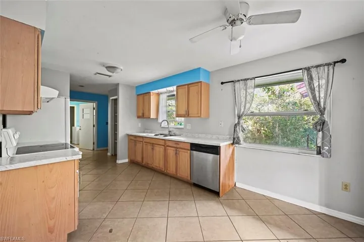 Kitchen featuring dishwasher, light tile patterned floors, ceiling fan, and a healthy amount of sunlight
