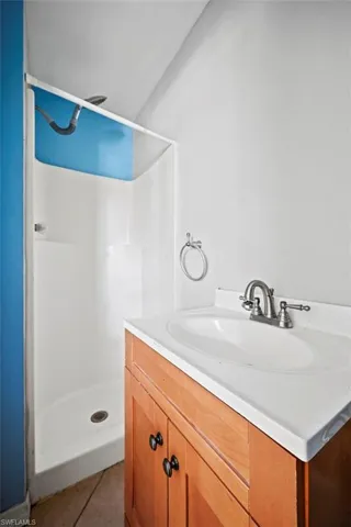 Bathroom featuring tile patterned floors, vanity, and walk in shower