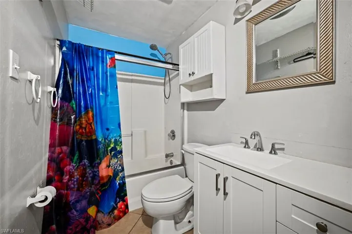 Full bathroom featuring tile patterned flooring, shower / bath combination with curtain, vanity, and toilet