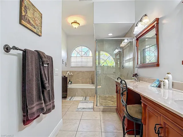 Bathroom with double vanity, a stall shower, light tile patterned floors, and a bath