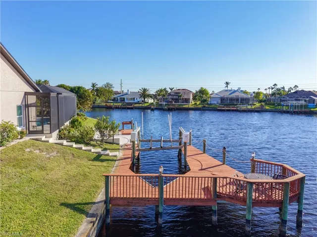 Dock with a water view, a yard, a residential view, a lanai, and boat lift