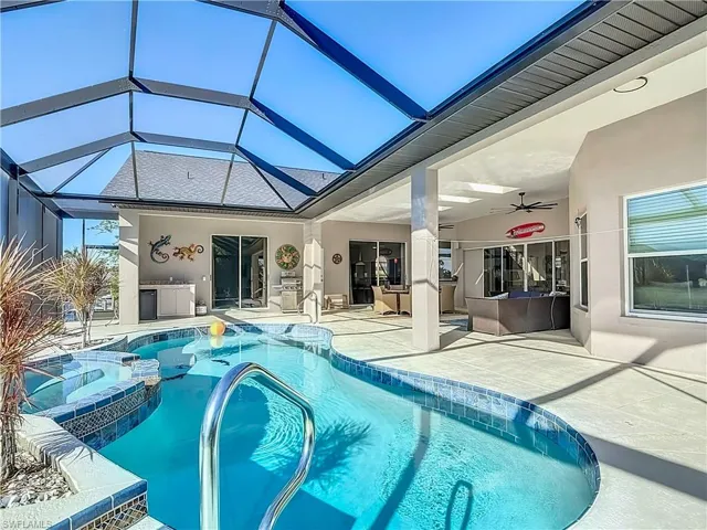 View of pool featuring a ceiling fan, glass enclosure, a patio area, and a pool with connected hot tub