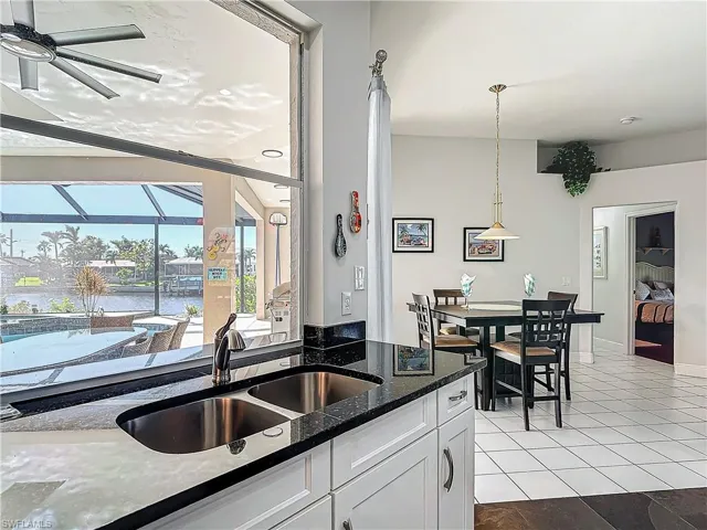 Kitchen featuring a sunroom, dark stone counters, a ceiling fan, white cabinets, and light tile patterned floors