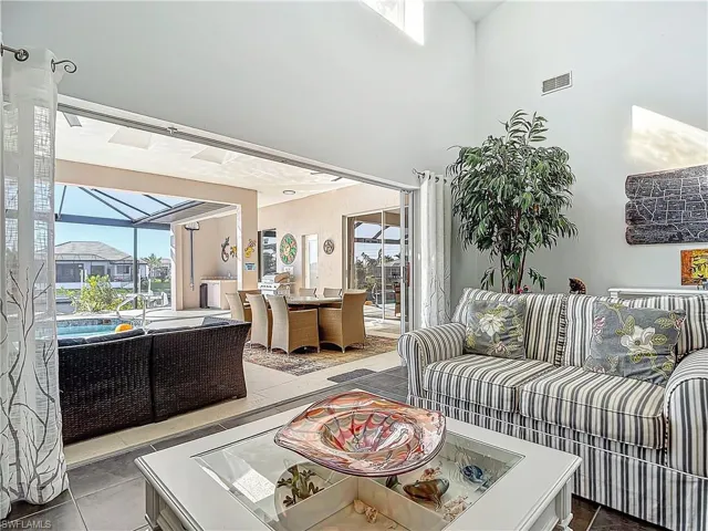 Living room featuring a sunroom, tile patterned floors, and a towering ceiling