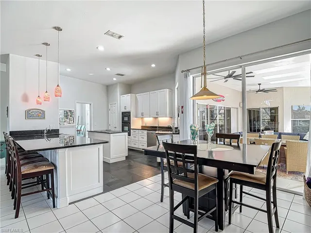 Kitchen with white cabinetry, a kitchen breakfast bar, ceiling fan, a peninsula, and decorative light fixtures