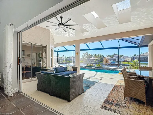 View of patio / terrace featuring a sunroom, ceiling fan, glass enclosure, and an outdoor living space