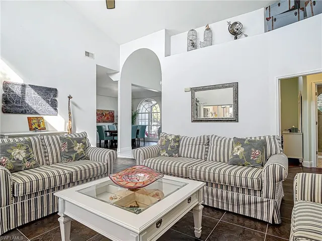 Living room featuring high vaulted ceiling, arched walkways, and dark tile patterned floors