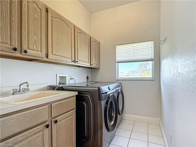 Laundry room featuring light tile patterned floors, separate washer and dryer, and cabinet space