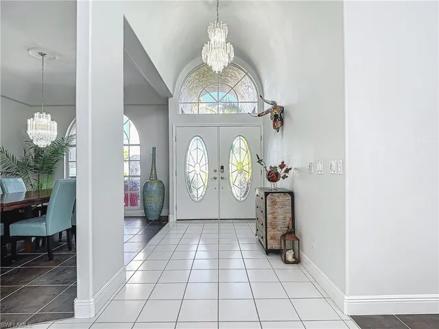 Entryway with a chandelier, dark tile patterned floors, and lofted ceiling