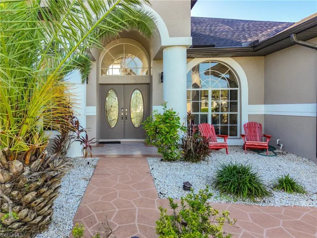 View of exterior entry featuring a shingled roof and stucco siding