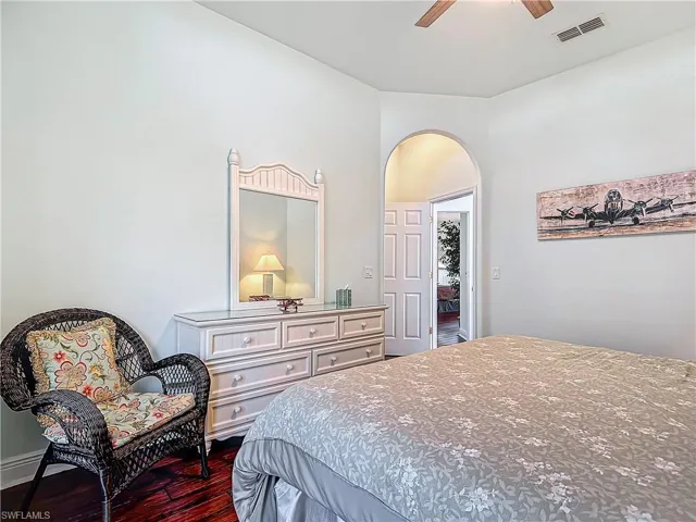 Bedroom with dark wood-type flooring, arched walkways, and ceiling fan