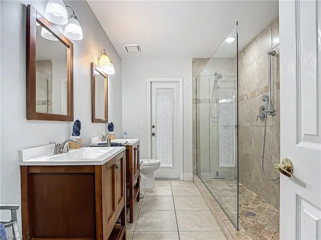 Bathroom with a stall shower, light tile patterned floors, and two vanities