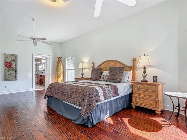 Bedroom with dark wood-style flooring, a ceiling fan, and ensuite bathroom