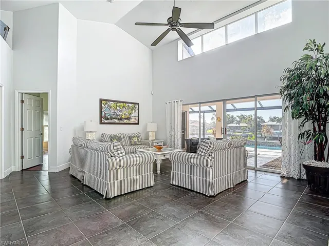 Tiled living room with plenty of natural light, ceiling fan, and high vaulted ceiling