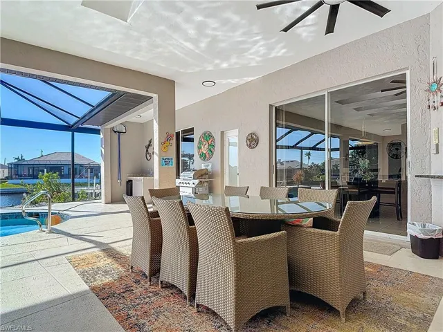 View of patio / terrace with glass enclosure, ceiling fan, a sunroom, an outdoor pool, and outdoor dining area