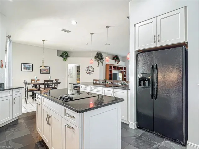 Kitchen with black appliances, white cabinetry, hanging light fixtures, dark stone countertops, and recessed lighting